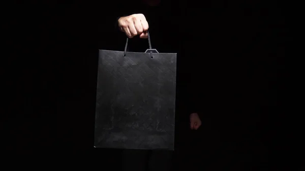 hand holds package on a black background. copy space. shopping, sale, discount