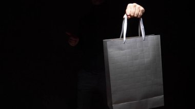 Siyah arka planda el ele tutuşan bir paket. kopyalama alanı. Alışveriş, indirim, indirim.