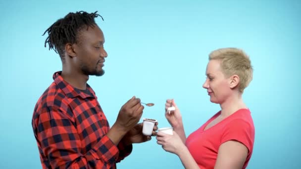 Afrikalı beyaz kadın çikolata ve kremalı yoğurt yiyor. mavi arkaplan — Stok video