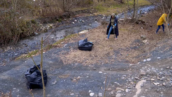 Çevresel sorunlar. Gönüllüler nehrin kıyısında çöp topluyor. — Stok fotoğraf
