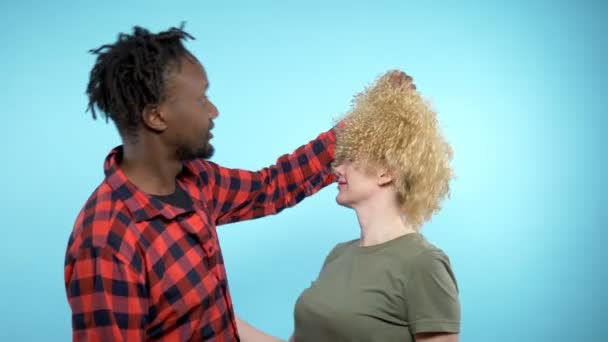 Afrikalı erkek ve beyaz kadın birlikte. Adam kızlarla peruğunu çıkarıyor. — Stok video