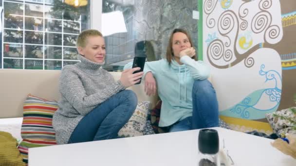 Duas mulheres estão sentadas juntas em um café informal — Vídeo de Stock