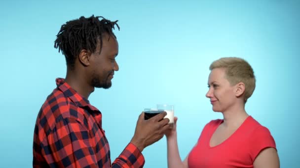 Αφρικανός και λευκή γυναίκα πίνουν μαύρο και άσπρο κοκτέιλ. μπλε φόντο — Αρχείο Βίντεο