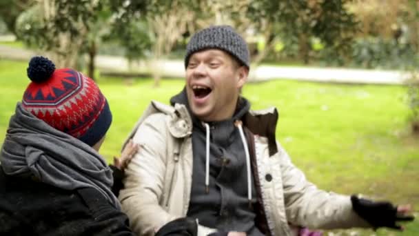 Una coppia di senzatetto, un uomo e una donna che si divertono seduti su una panchina di Park. umorismo — Video Stock