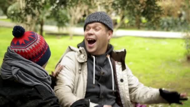 Een dakloos stel, een man en vrouw die plezier hebben in een bankje in het park. humor — Stockvideo