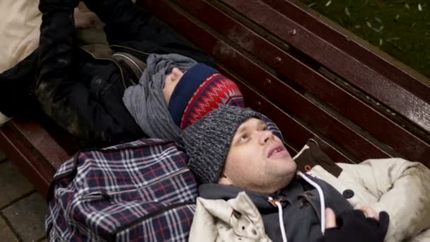 A homeless couple, a man and woman on a bench in a city Park — Stock Video