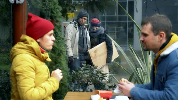 Een paar daklozen mannen en vrouwen vragen om voedsel van bezoekers van een straat cafe — Stockvideo