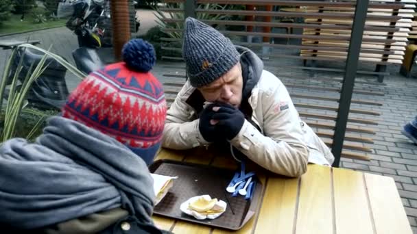 Casal sem-teto, homem e mulher comendo sobras de uma mesa em um café de rua — Vídeo de Stock