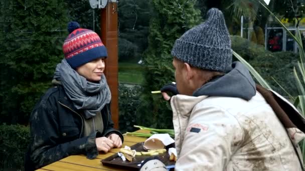 Hajléktalan pár, férfi és nő, akik egy utcai kávézó asztaláról eszik a maradékot. — Stock videók