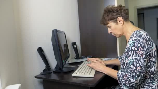 Ältere Frau am Computer sitzt an einem Tisch im Homeoffice — Stockvideo