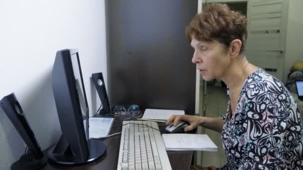 Bilgisayarın başındaki yaşlı kadın ofisteki bir masada oturuyor. — Stok video