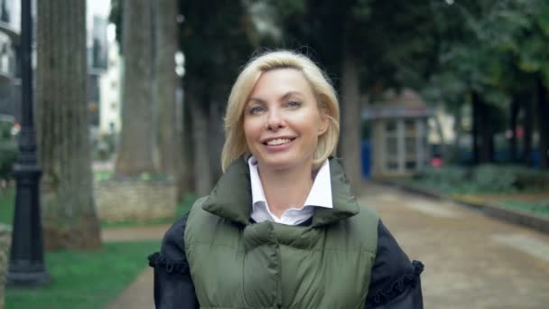 Красива стильна модна блондинка, що йде в міському парку восени — стокове відео