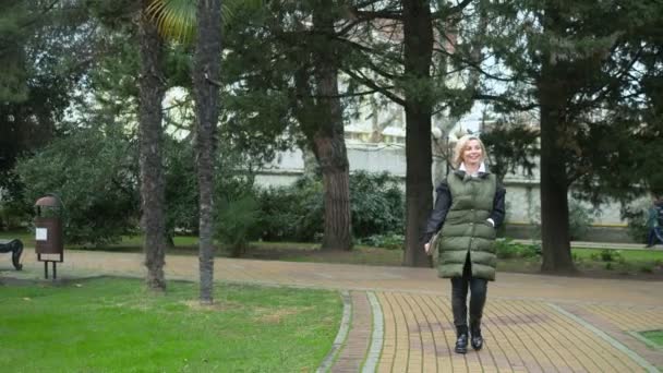 Hermosa mujer rubia de moda elegante caminando en un parque de la ciudad en otoño — Vídeos de Stock