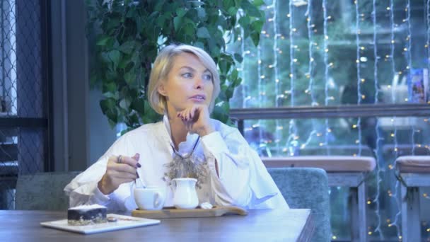 Schöne elegante elegante blonde Frau, die sich in einem Café ausruht — Stockvideo