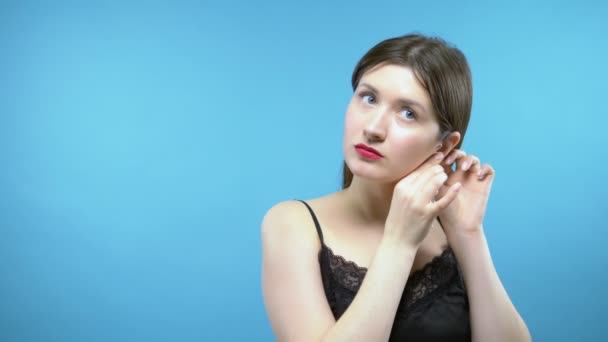 Porträtt av en vacker flicka. blå bakgrund. flickan bär örhängen — Stockvideo