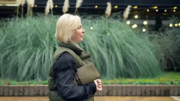 Hermosa mujer rubia de moda elegante caminando en un parque de la ciudad en otoño — Vídeos de Stock