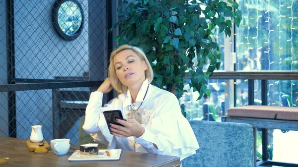 Elegante mulher loira elegante usando telefone móvel sentado em um café — Fotografia de Stock