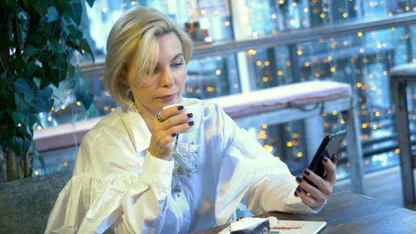 Elegante mulher loira elegante usando telefone móvel sentado em um café — Fotografia de Stock