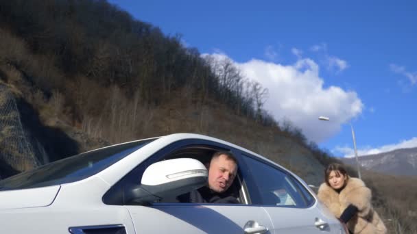 Dos hermosas chicas empujan el coche roto en la carretera. un hombre se sienta detrás del volante — Vídeo de stock