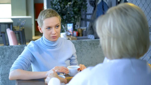 Дві красиві стильні жінки блондинки спілкуються сидячи в кафе — стокове фото