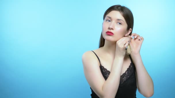 Retrato de uma menina bonita. fundo azul. a menina usa brincos — Vídeo de Stock