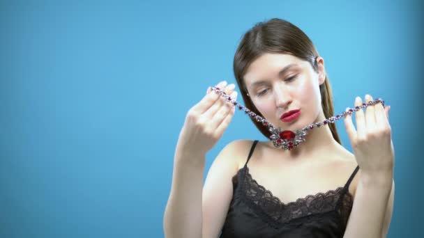 Beautiful young girl wears a necklace. blue background — Stock Video