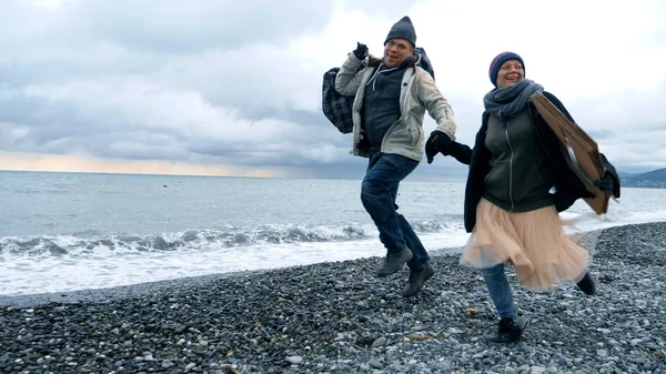 Glückliches obdachloses Paar, ein Mann und eine Frau laufen am Strand — Stockfoto