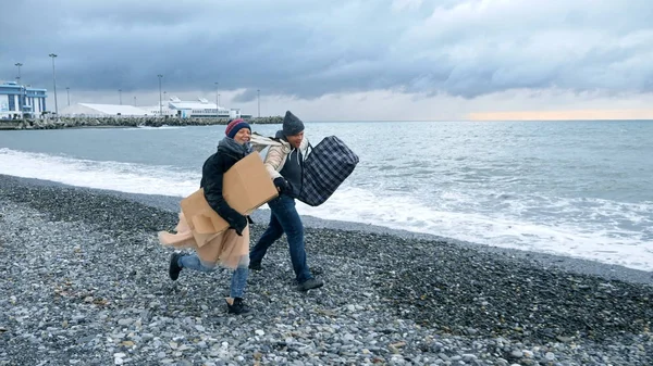 Heureux couple de sans-abri, un homme et une femme courant sur la plage — Photo