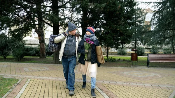 Sepasang pria tunawisma dan seorang wanita berjalan di taman kota — Stok Foto