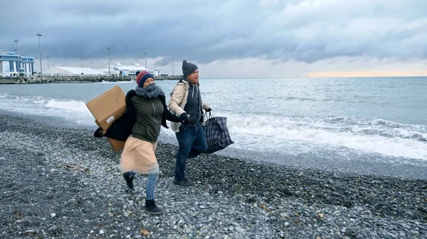 Ευτυχισμένο ζευγάρι αστέγων, ένας άντρας και μια γυναίκα τρέχουν στην παραλία. — Φωτογραφία Αρχείου