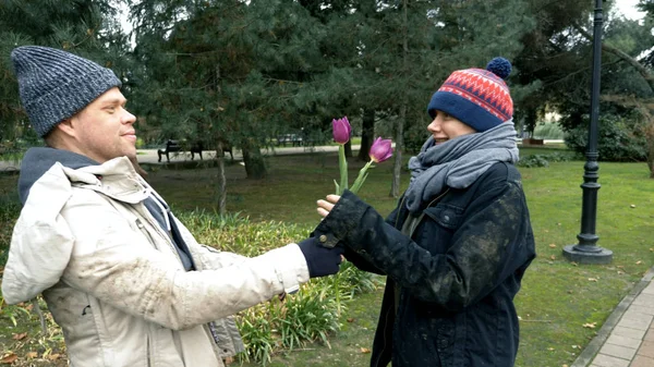 Бездомний чоловік збирає квіти на клумбі в парку для своєї жінки — стокове фото