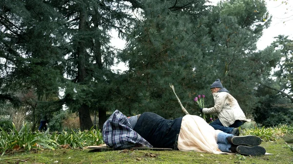 Pria tunawisma memetik bunga di tempat tidur bunga di taman untuk istrinya — Stok Foto