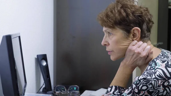 Idős nő a számítógépnél ül egy asztalnál az otthoni irodában — Stock Fotó