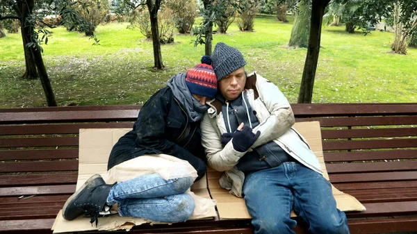 Бездомная пара, мужчина и женщина на скамейке в городском парке — стоковое фото