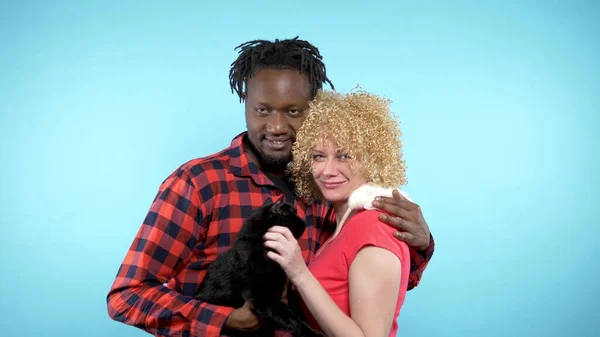 Hombre africano y mujer caucásica. sosteniendo un gato negro y una rata blanca . — Foto de Stock