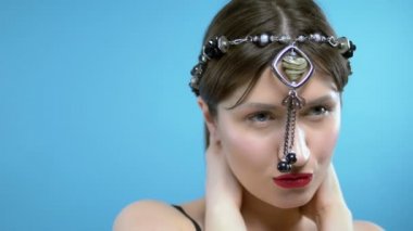 Kafasında kalp şeklinde bir kolye olan siyah akik boncuklar takıyor.