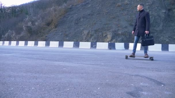 Ung affärsman med portfölj rider på en elektrisk bräda på motorvägen — Stockvideo