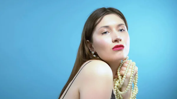 Beautiful young girl with pearls and earrings on a blue background — Stock Photo, Image