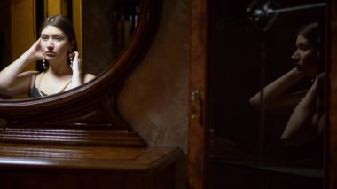 Alacakaranlıkta aynanın önünde oturan kolye takan güzel kız..