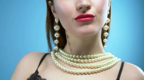 Belle jeune fille avec des perles et des boucles d'oreilles sur un fond bleu — Photo