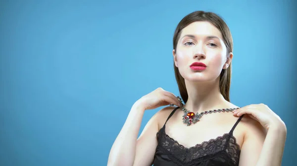 Beautiful young girl wears a necklace. blue background — Stock Photo, Image