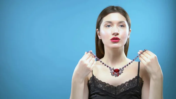 Beautiful young girl wears a necklace. blue background — Stock Photo, Image