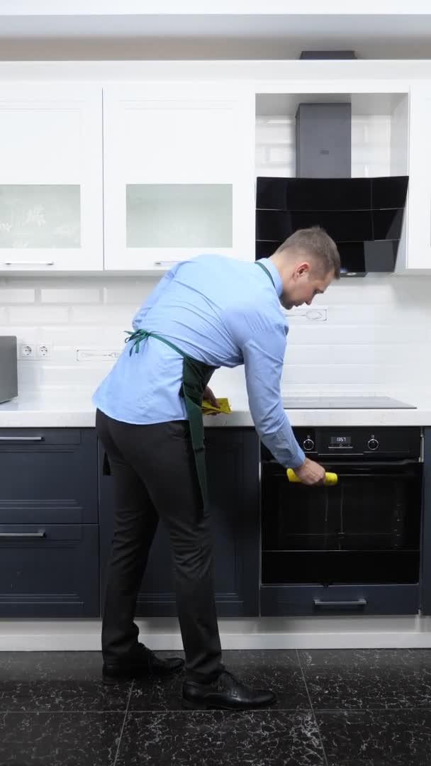 Verticaal beeld. knappe man met das en schort trekt taarten uit de oven — Stockvideo