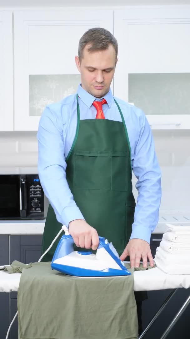 Disparo vertical. hombre guapo en corbata y delantal acariciando ropa — Vídeos de Stock