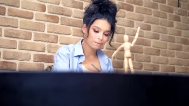 Beautiful brunette girl draws a sketch with a wooden mannequin — 비디오