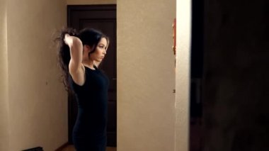 Kız, evinde aynanın önünde duran bir saç teli yapıyor.