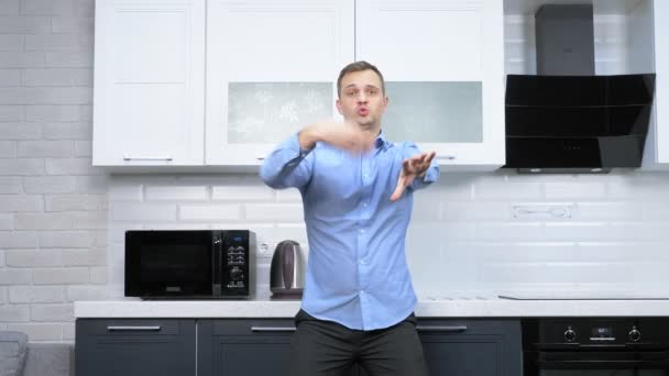 Ένας νεαρός όμορφος άντρας χορεύει στην κουζίνα. τρόπος ζωής — Αρχείο Βίντεο