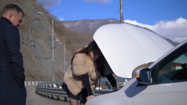 Una mujer está reparando un coche. Un hombre pasa por aquí, ignorándola. humor . — Vídeos de Stock