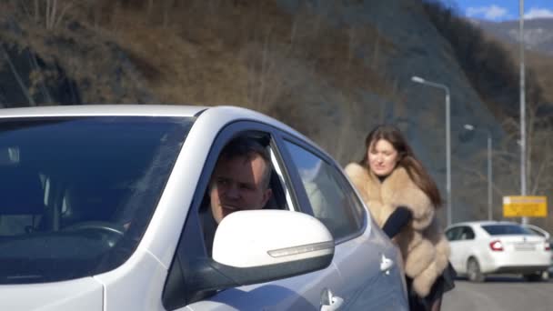 Dos hermosas chicas empujan el coche roto en la carretera. un hombre se sienta detrás del volante — Vídeo de stock