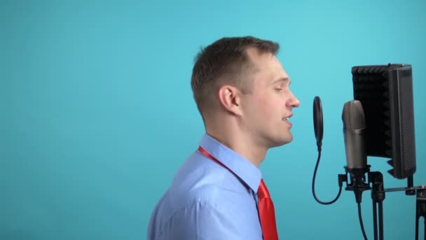 Un joven guapo con corbata cantando en un micrófono. primer plano — Vídeo de stock